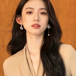 Asymmetric pearl horse tassel earrings with gold plating and rhinestones on model