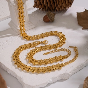 Artistic layout of a gold geometric chain necklace on a white stone surface with vintage decor