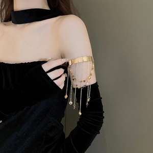 Detailed view of a gold armlet with heart tassels worn on a black velvet sleeve