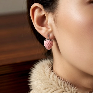 Macro shot of a sweet pink strawberry-shaped stud earring worn by an Asian model