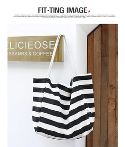 Detail of canvas tote bag with black and white stripes and thick rope handles on wall