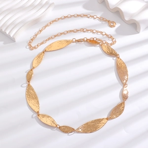 Detail of golden bohemian waist chain featuring hammered olive leaf metallic plates