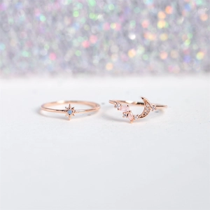 Detail of rose gold star and moon rings with blue and pink gemstones on bokeh background
