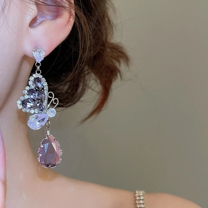 Macro shot of silver butterfly earrings with purple teardrop zircon and clear crystal pavé