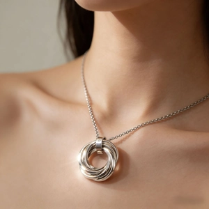Close-up of interlocking silver rings pendant necklace on model showing metallic texture