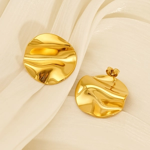 Modern minimalist irregular wavy gold stud earrings on soft cream silk fabric