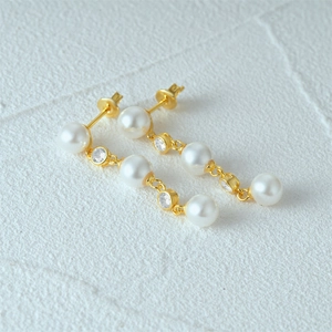 Macro shot of long S925 silver gold-plated tassel earrings with pearls and cubic zirconia
