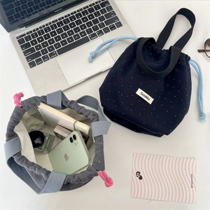 Detailed close-up of wool polka dot drawstring bucket bags on a desktop with daily items