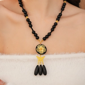 Detail of vintage beaded necklace with gold flower pendant and black water-drop tassels