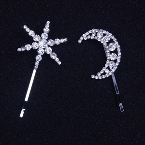 Sparkling star and moon hair clip set with white rhinestones on black background