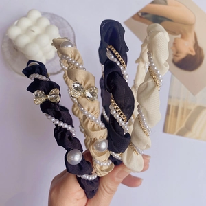 Elegante gevlochten haarband met parels en strass getoond in een hand-held close-up