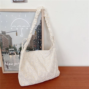 Floral canvas tote bag with daisy pattern and ruched shoulder strap on wooden desk