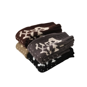Close-up of knit wool blend gloves featuring white reindeer and snowflake festive patterns