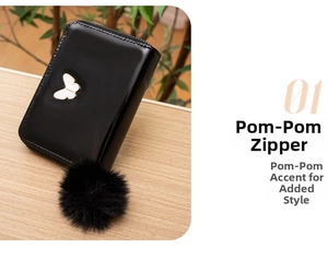 Detail of black glossy leather purse with white butterfly clasp and plush pompom pendant