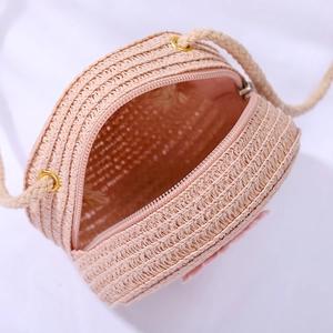 Detail of children's pink woven straw crossbody bag with zipper and rope strap
