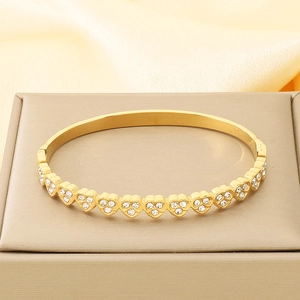 Close-up of gold stainless steel heart bracelet with sparkling zircon stones on satin