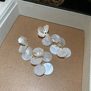 Detail of floral earrings with shimmering acrylic discs and golden rings on brown tray