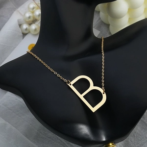 Detailed close-up of capital B pendant necklace on a black mannequin display neck