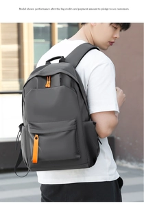 Model wearing a gray waterproof oxford backpack with orange zipper details in a city setting