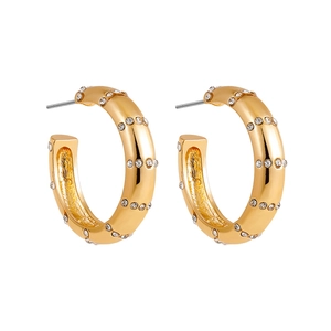 Vue macro de boucles d'oreilles créoles en C dorées 18K avec cristaux étincelants