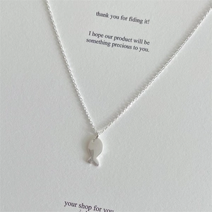 Close-up of a minimalist 925 sterling silver fish pendant on a white gift card