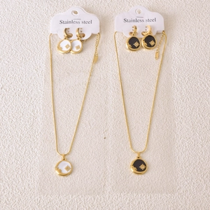 Detail of gold stainless steel necklace sets with sunburst pendants in black and white