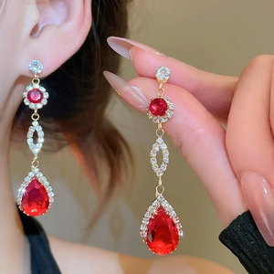 Detail of luxury gold earrings featuring teardrop red gems and sparkling crystals