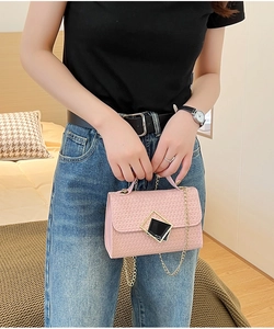 Detalle de bolso bandolera rosa con textura ondulada y correa de cadena dorada
