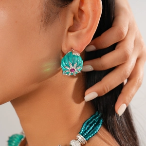 Detail of green resin earring with silver flower inlay and sparkling red gemstone