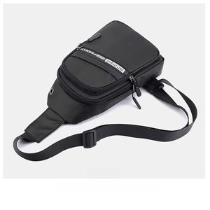 Detail of black chest bag showing multiple zipper compartments and adjustable strap