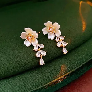Floral tassel earrings with white petals and crystal water drops on green velvet