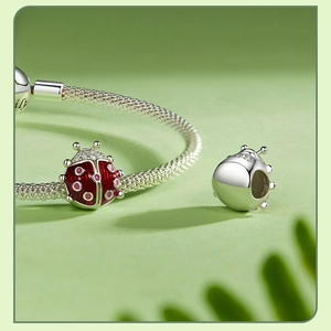 Macro detail of S925 sterling silver ladybug charm with red and pink enamel finish