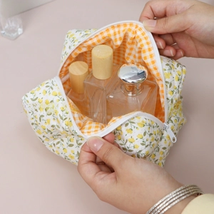 Detail view of cotton floral makeup bag with orange checkered lining showing large interior