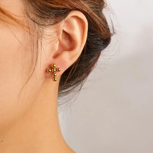Detail of vintage gold beaded cross earrings featuring polished metallic spherical texture