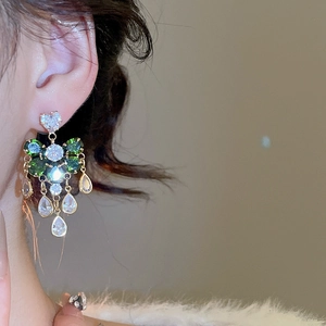 Close-up of sparkling green zircon droplet tassel earrings worn by a female model