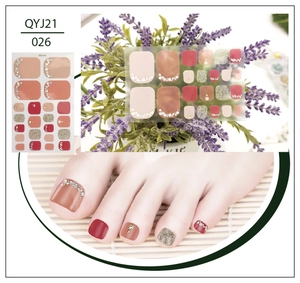 Detail of nude and dark red toe nail stickers with gold glitter and rhinestones