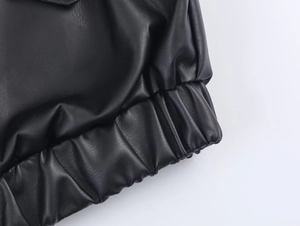 Detailed close-up of elastic hem and cuff on black leather jacket with sleek finish
