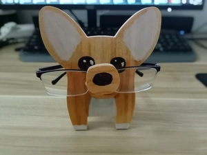 Detail of wooden Corgi dog glasses stand holding spectacles on a desk setup