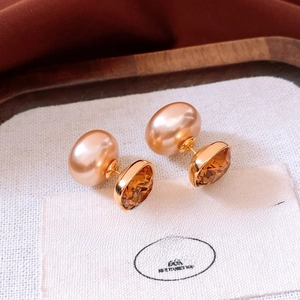 Macro detail of double-sided stud earrings with champagne pearl and amber crystal texture
