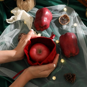 Red velvet Christmas drawstring gift bag held by hand, perfect for apples or small gifts
