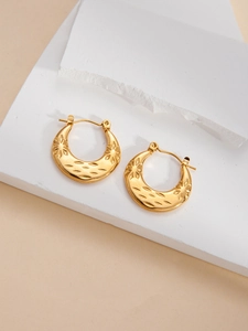 Detailed macro view of vintage gold C-shape earrings featuring intricate starburst engravings