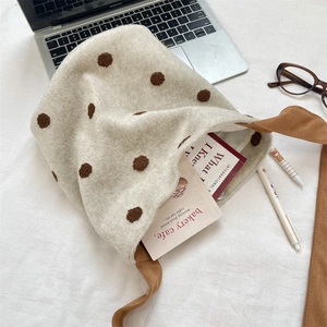 Vista dettagliata di una borsa in lana a pois con laptop e oggetti da scrivania