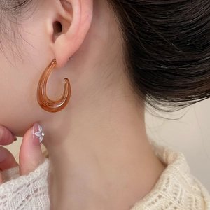 Amber acrylic C-shape hoop earring worn by a model to show elegant transparency and size