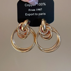 Macro detail of interlocked triple layer golden hoop earrings made of copper