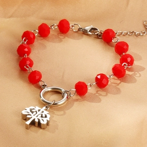 Macro detail of red faceted crystal beads and silver Tree of Life pendant on a bracelet