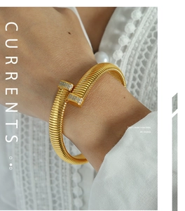 Detailed view of a gold-plated ribbed open bracelet with zircon square ends on a wrist