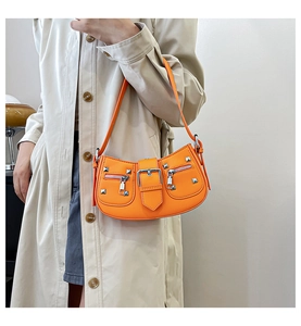 Detail of orange hobo bag with silver rivets and studs on a light coat model