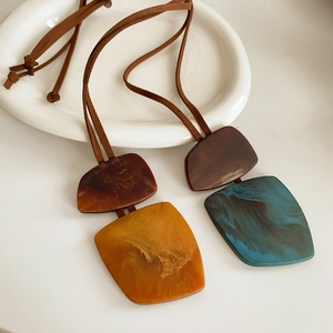 Detail of vintage geometric pendant necklaces with marble texture on ceramic plate