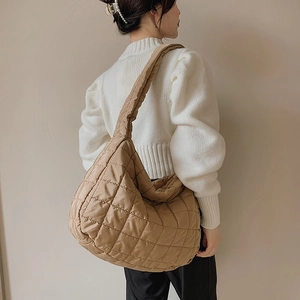 Khaki quilted nylon tote bag with adjustable strap shown on model shoulder in side view