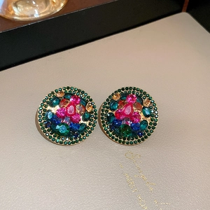 Close-up of vintage geometric earrings featuring colorful rhinestones and pink crystal center